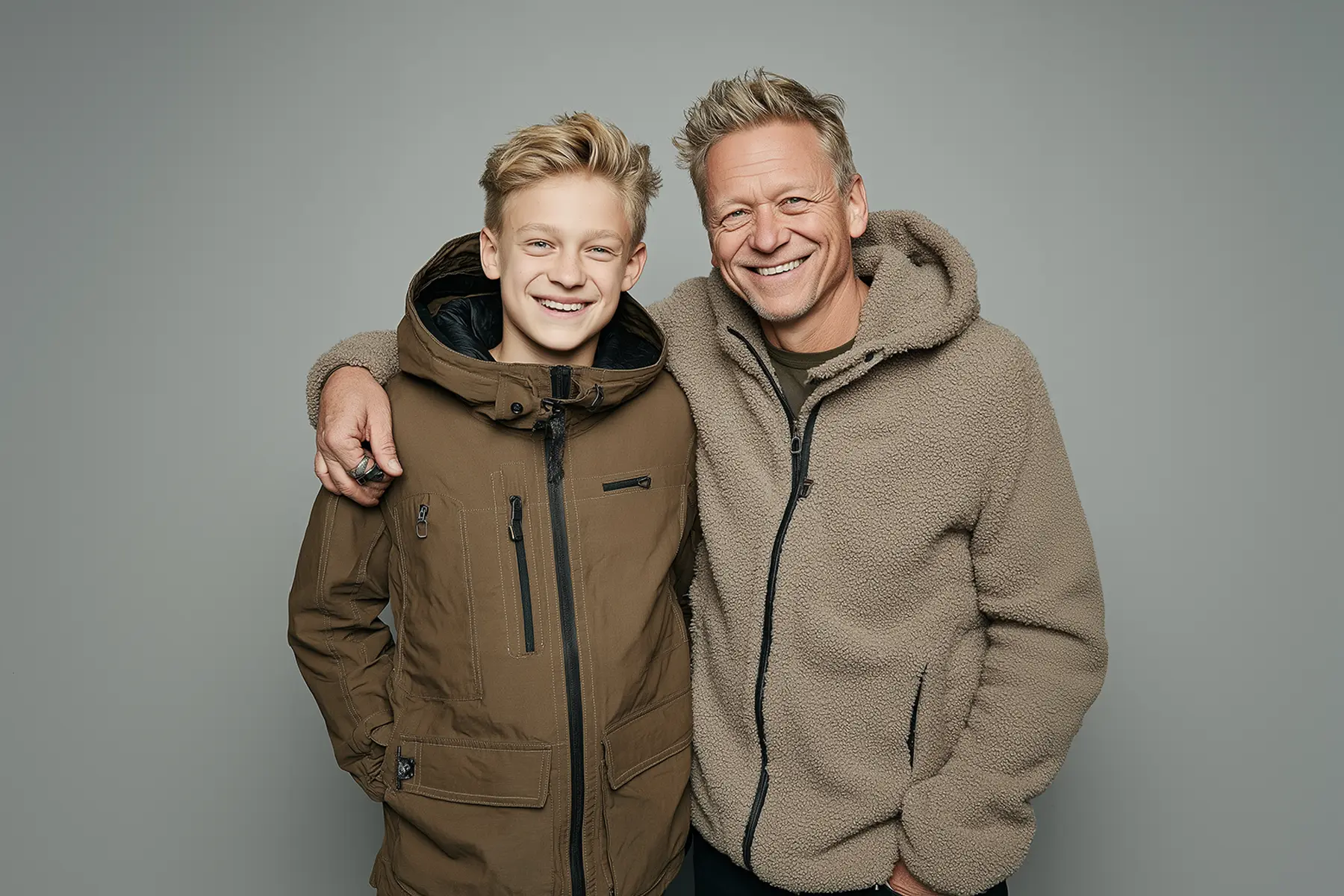 AI-generated studio portrait of a smiling man and a boy standing together, with subtle inconsistencies in the hands and clothing details