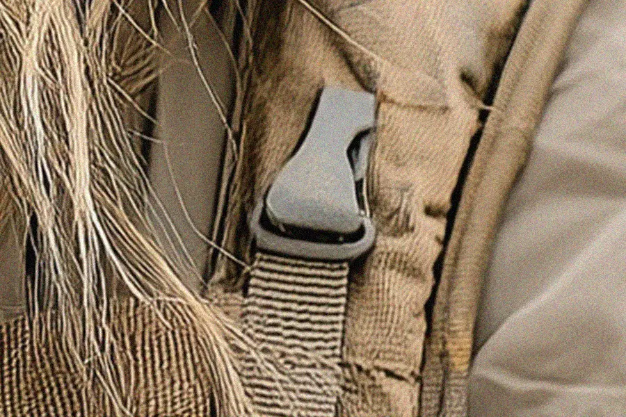 Zoomed-in detail of an AI-generated backpack strap attachment with unnatural shape and fabric structure.